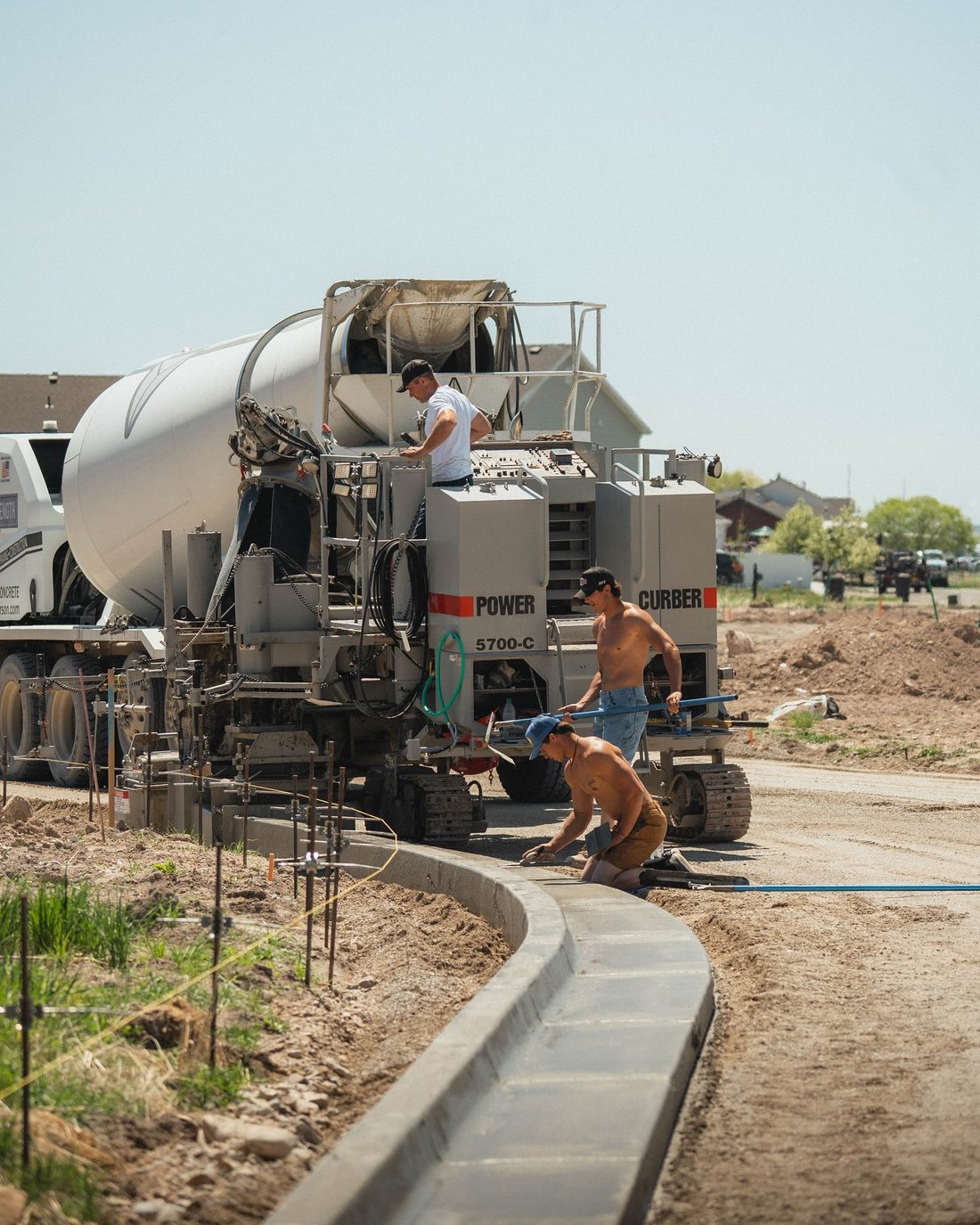 Crew running a curb machine and hand finishing a curved curb