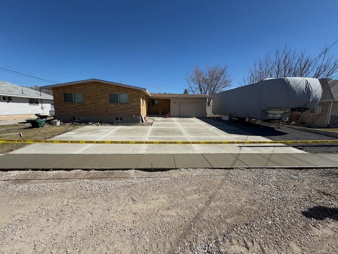 New concrete driveway and sidewalk in front of a brick home